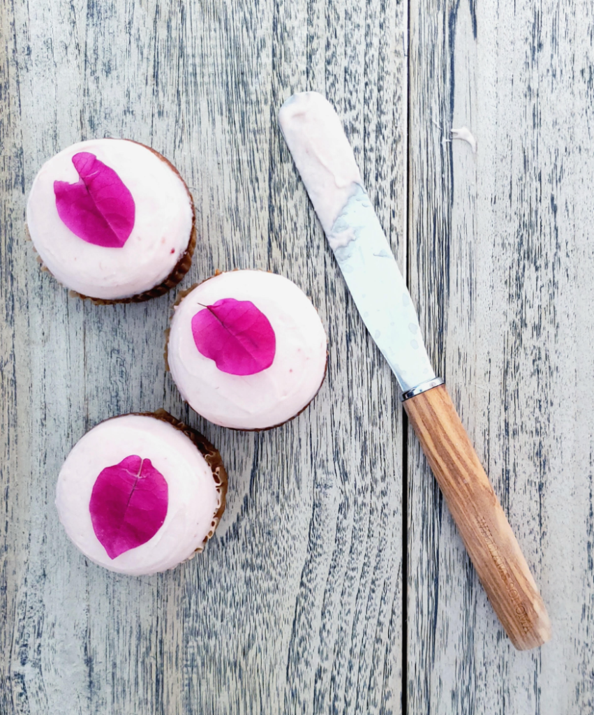 functional image three rhubarb muffins with pink rhubarb cream cheese icing spatula flower petals