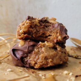 vegan almond butter cookies. side view of two cookies stacked on top of each other. top cookie has been bitten so you can see the inner crumb.