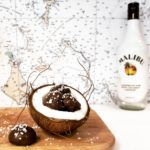 functional image dark chocolate coconut rum truffles cradled in a ripe cracked hairy coconut half malibu rum bottle navigation chart in background cutting board under coconut