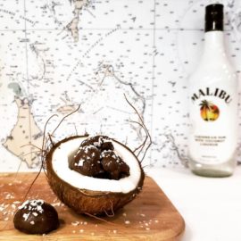 functional image dark chocolate coconut rum truffles cradled in a ripe cracked hairy coconut half malibu rum bottle navigation chart in background cutting board under coconut