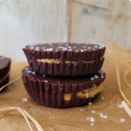 dark chocolate peanut butter cups. side view of homemade peanut butter cups stacked 2 high on brown parchment paper