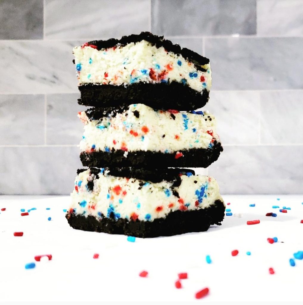 functional image oreo funfetti cheesecake bars three square slices stacked on white so you can see the side view layers with multi color funfetti sprinkles all round