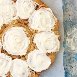 soft and fluffy cinnamon rolls with cream cheese icing. top down, zoomed in view of rolls baked in a circular pan.