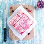 functional image cranberry swirl cheesecake bars with graham cracker crust on a cutting board with a knife