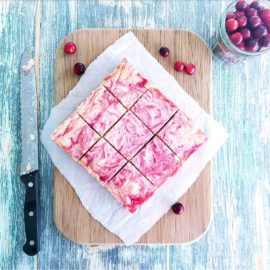 functional image cranberry swirl cheesecake bars with graham cracker crust on a cutting board with a knife