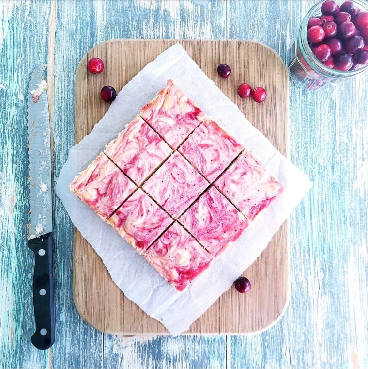 functional image cranberry swirl cheesecake bars with graham cracker crust on a cutting board with a knife