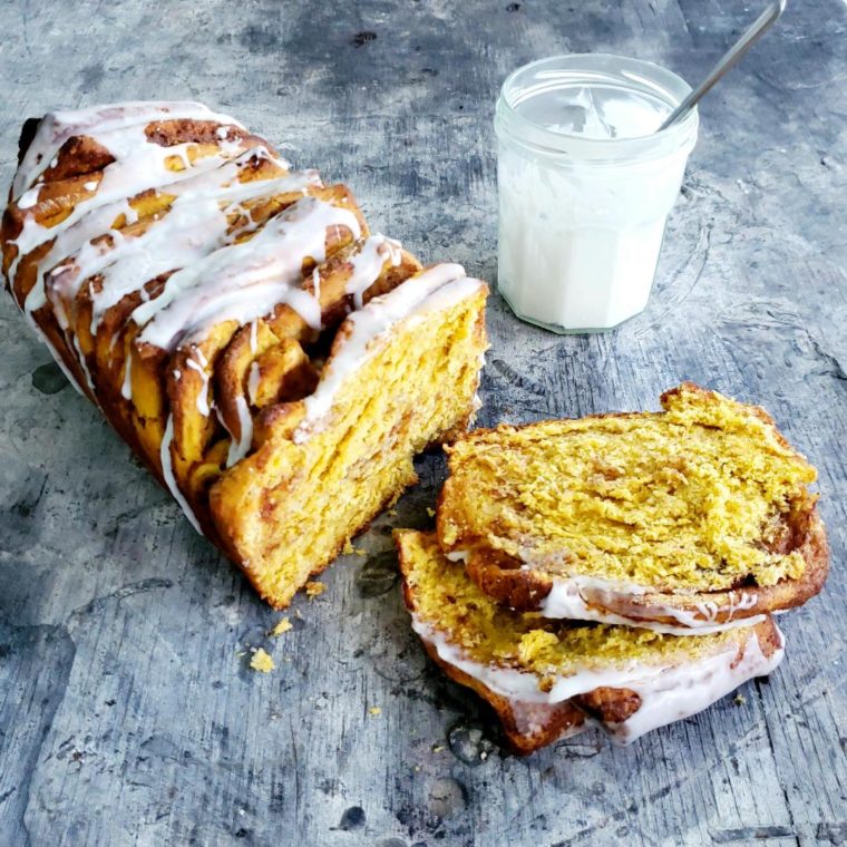 pumpkin pull apart bread loaf with two slices separated and a glass jar of icing