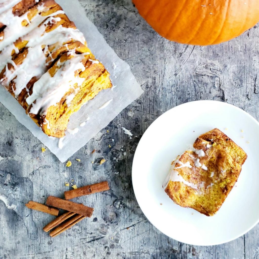 functional image pumpkin pull apart bread top down styled with a pumpkin cinnamon sticks and a slice of pumpkin bread