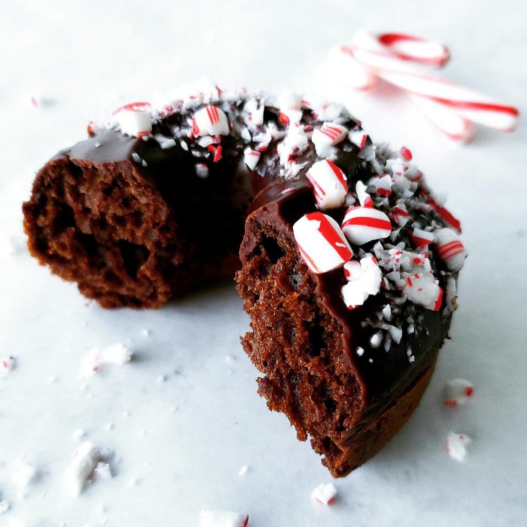  chocolate donuts with peppermint schnapps glaze with a bite out of it and garnished with crushed candy canes