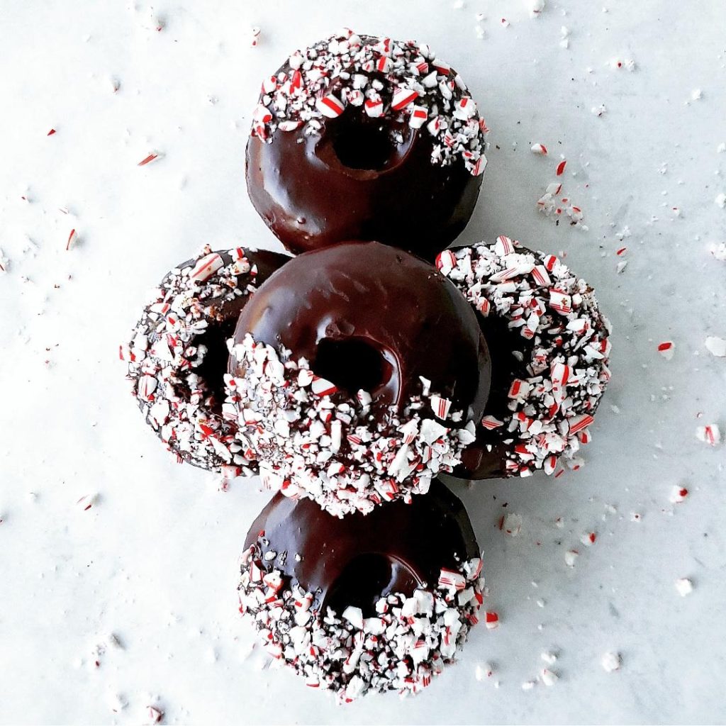 chocolate peppermint donuts with crushed candy canes piled up in a formation top down photo 5 donuts
