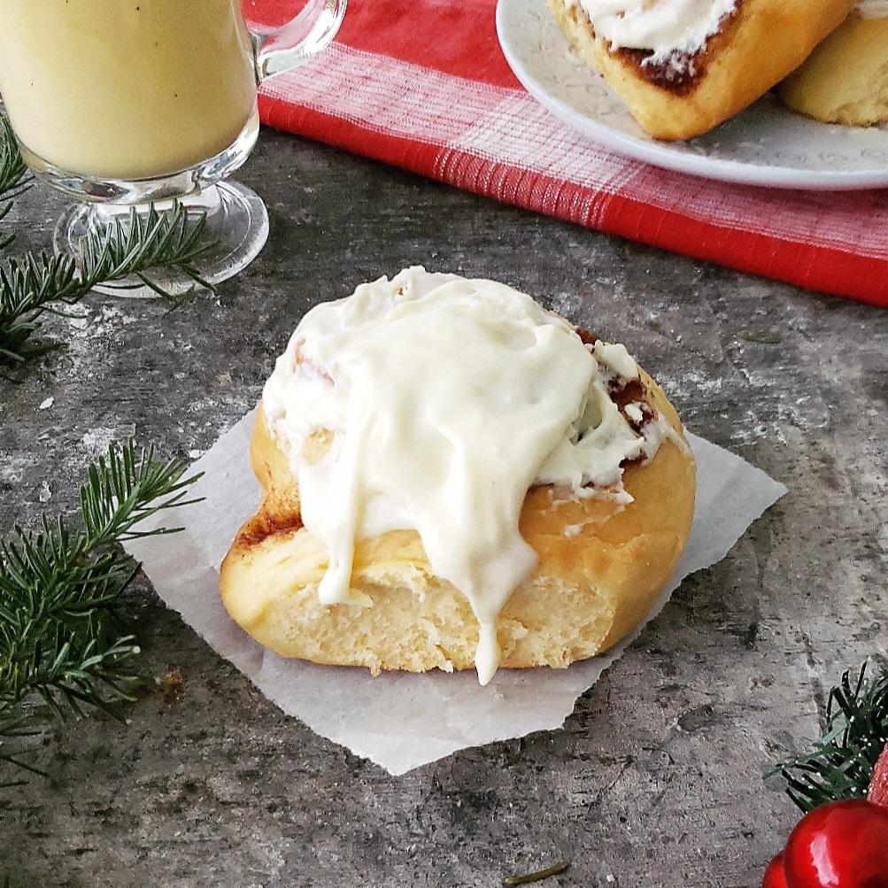 functional image spiked eggnog cinnamon rolls recipe closeup with dripping cream cheese frosting