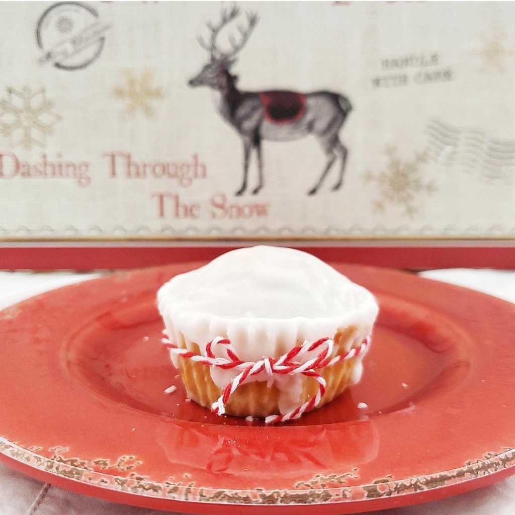 eggnog muffins recipe with eggnog glaze spiked with rum single muffin on red plate with reindeer in background