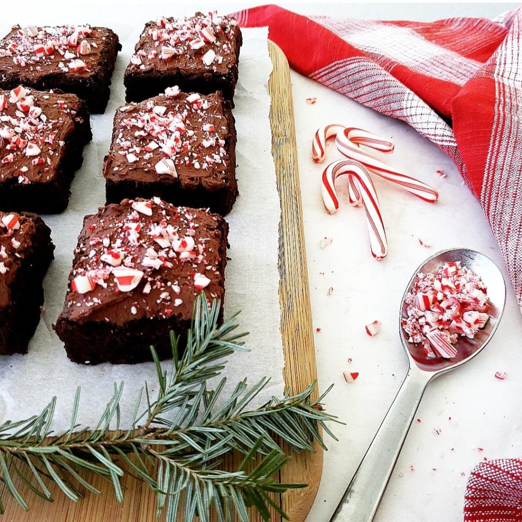 functional image peppermint brownies with whipped ganache and crushed candy canes on a cutting board