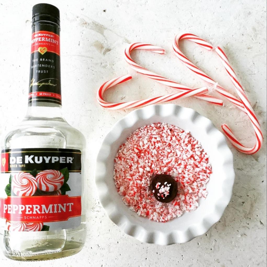 functional image peppermint schnapps christmas truffles with bottle of dekuyper schnapps and a bowl of crushed candy canes with one truffle and four candy canes