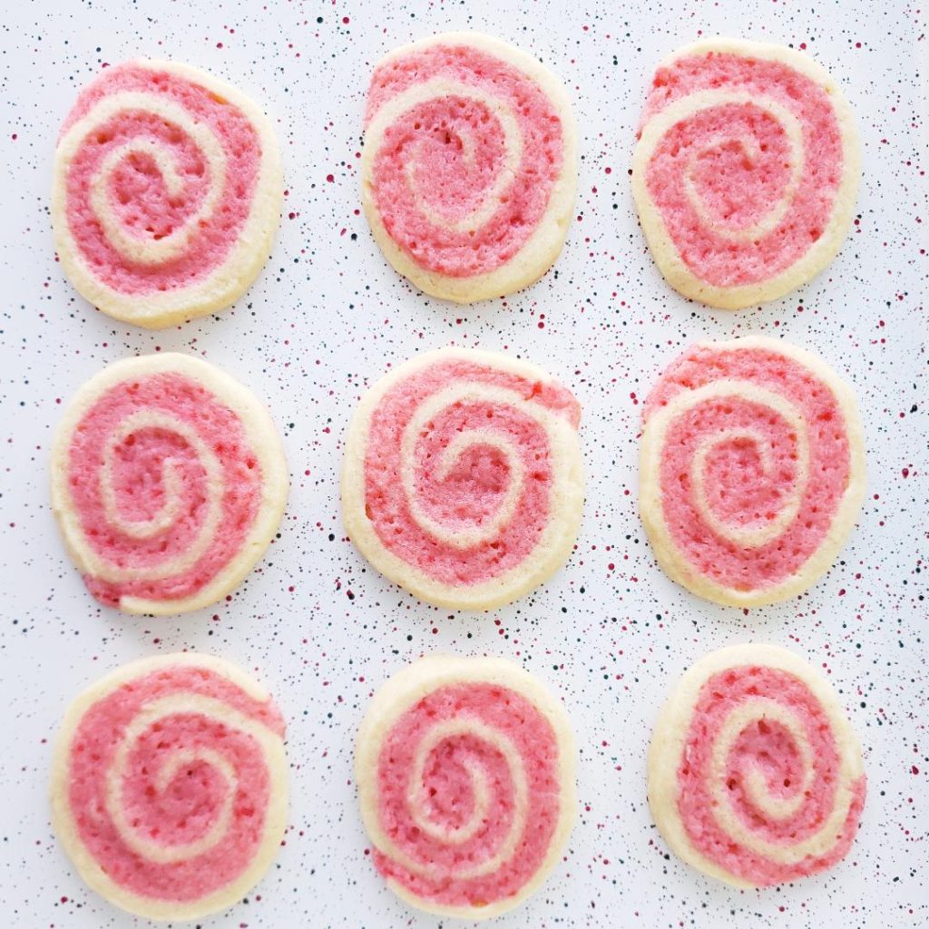 peppermint pinwheel cookies with crushed candy canes 9 baked cookies on a speckled baking pan
