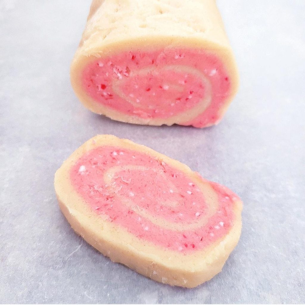 pinwheel cookies with crushed candy canes log of uncooked dough with one slice cut