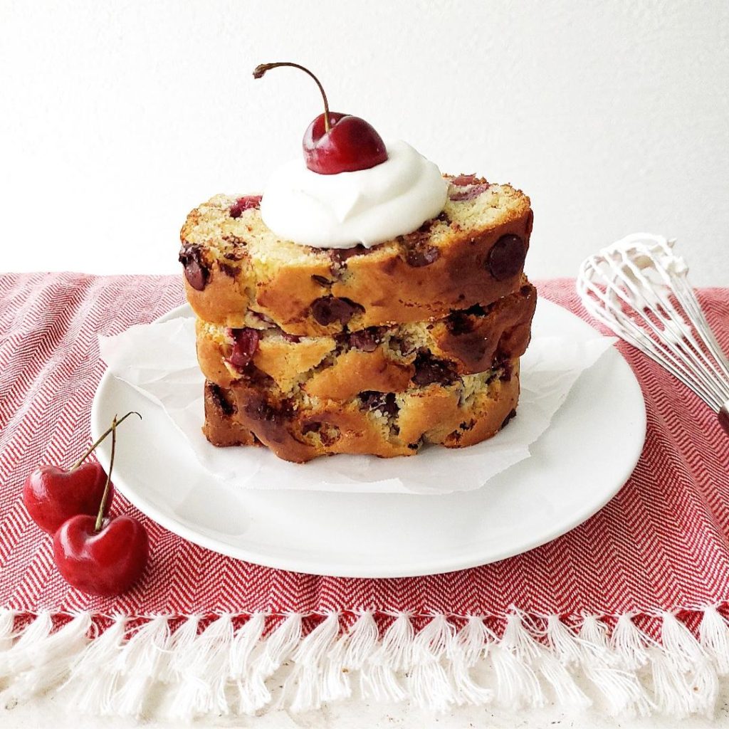 functional image cherry chocolate chip bread quick bread loaf three slices stacked on a plate with whipped cream and fresh cherries