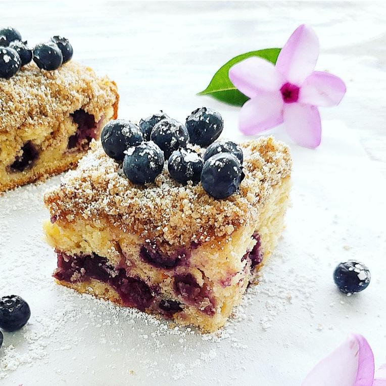 blueberry coffee cake with sour cream close up slice with fresh blueberries crumb topping and flowers blueberry sour cream coffee cake