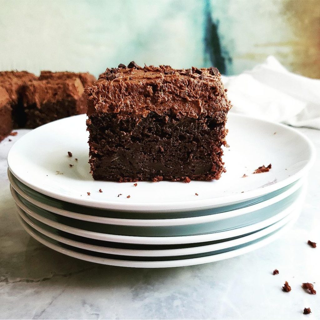 functional image chocolate cake zucchini big fat slice on a stack of plates with chocolate buttercream frosting zucchini cake