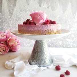 functional image raspberry cheesecake on a cake stand with fresh raspberries and a pink rose