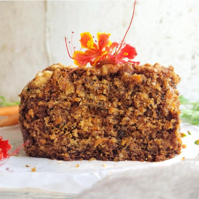 carrot bread with walnuts. side view of sliced loaf so you can see the moist inner crumbs. bread is topped with yellow and orange flowers.