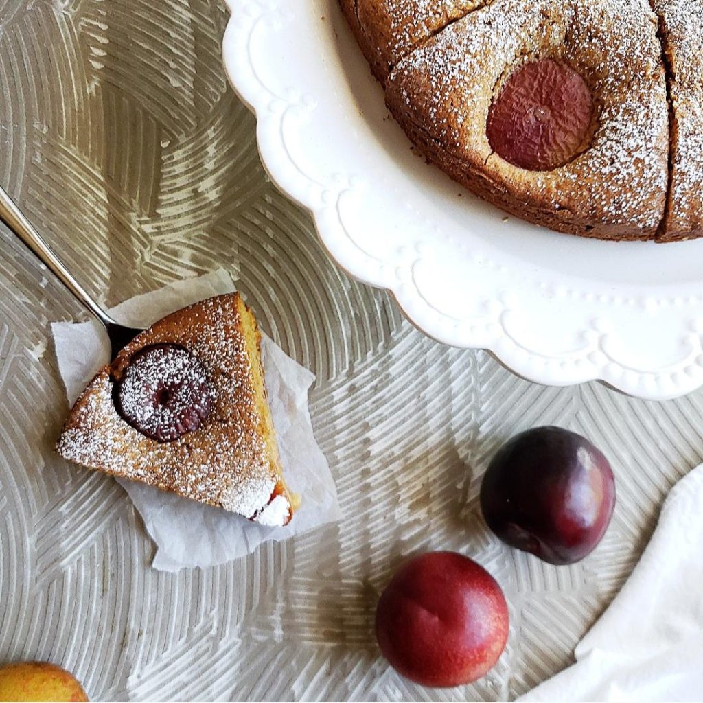 functional image plum cake on a cake stand with one slice on a pie server plum torte cake with plums