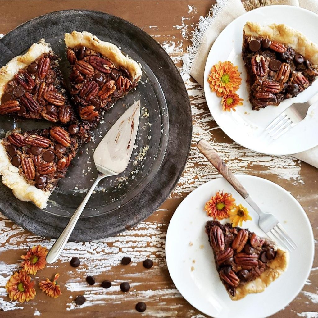 functional image chocolate chip pecan pie with a pie server and two plates with fall flowers