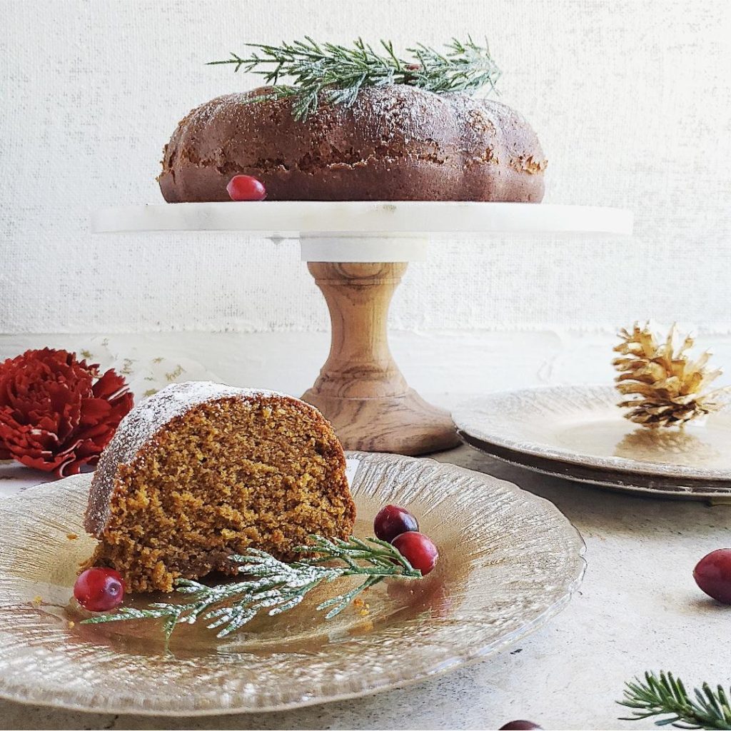 gingerbread bundt cake on a cake stand with fresh cranberries