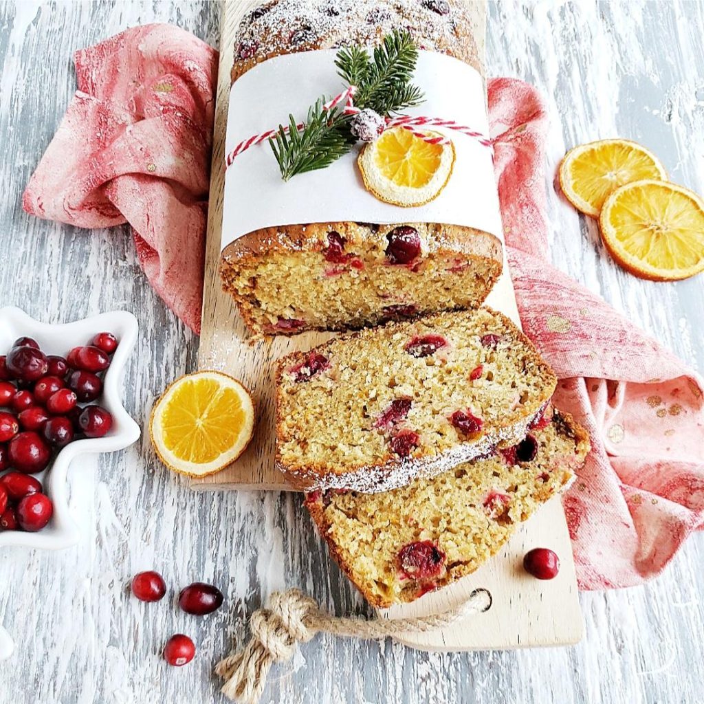 functional image cranberry orange bread cranberry loaf wrapped for gift giving with two slices cut and fresh cranberries and dehydrated orange slices