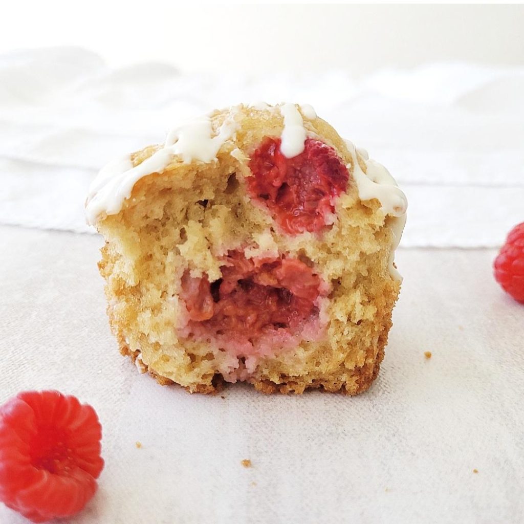 functional image white chocolate raspberry muffin with a bite out of it so you can see the interior crumbs and raspberries