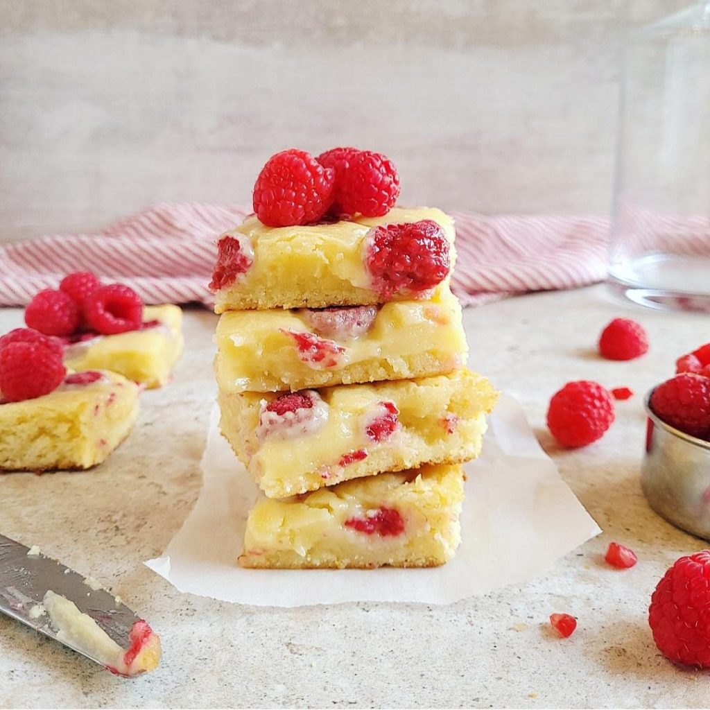 raspberry white chocolate blondies stacked 4 high with fresh raspberries on top side view