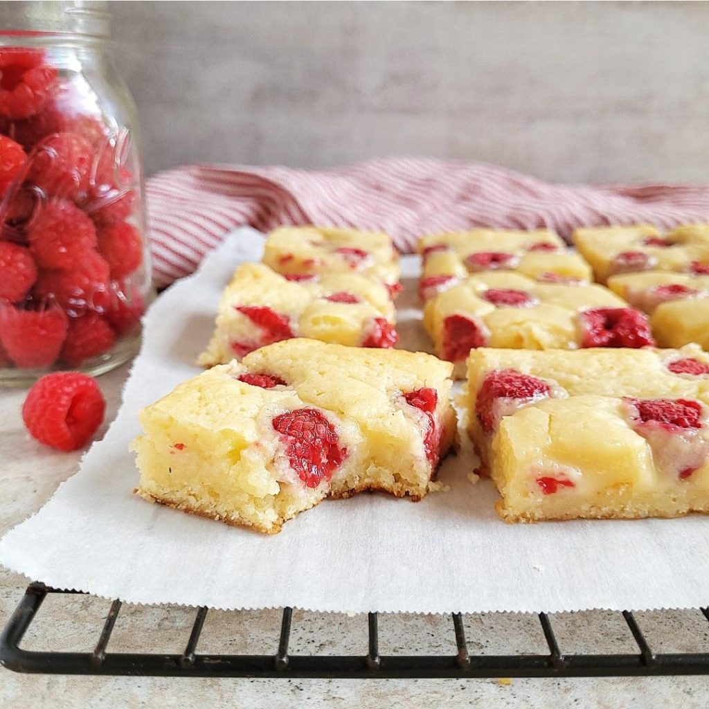 functional image raspberry white chocolate blondies cut into squares one with a bite missing