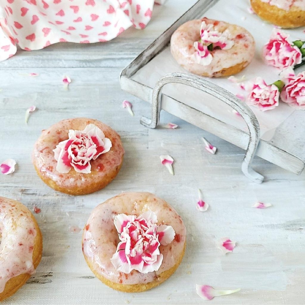 functional image cherry donuts with cherry vanilla glaze and pink carnations on a gray background with a gray tray