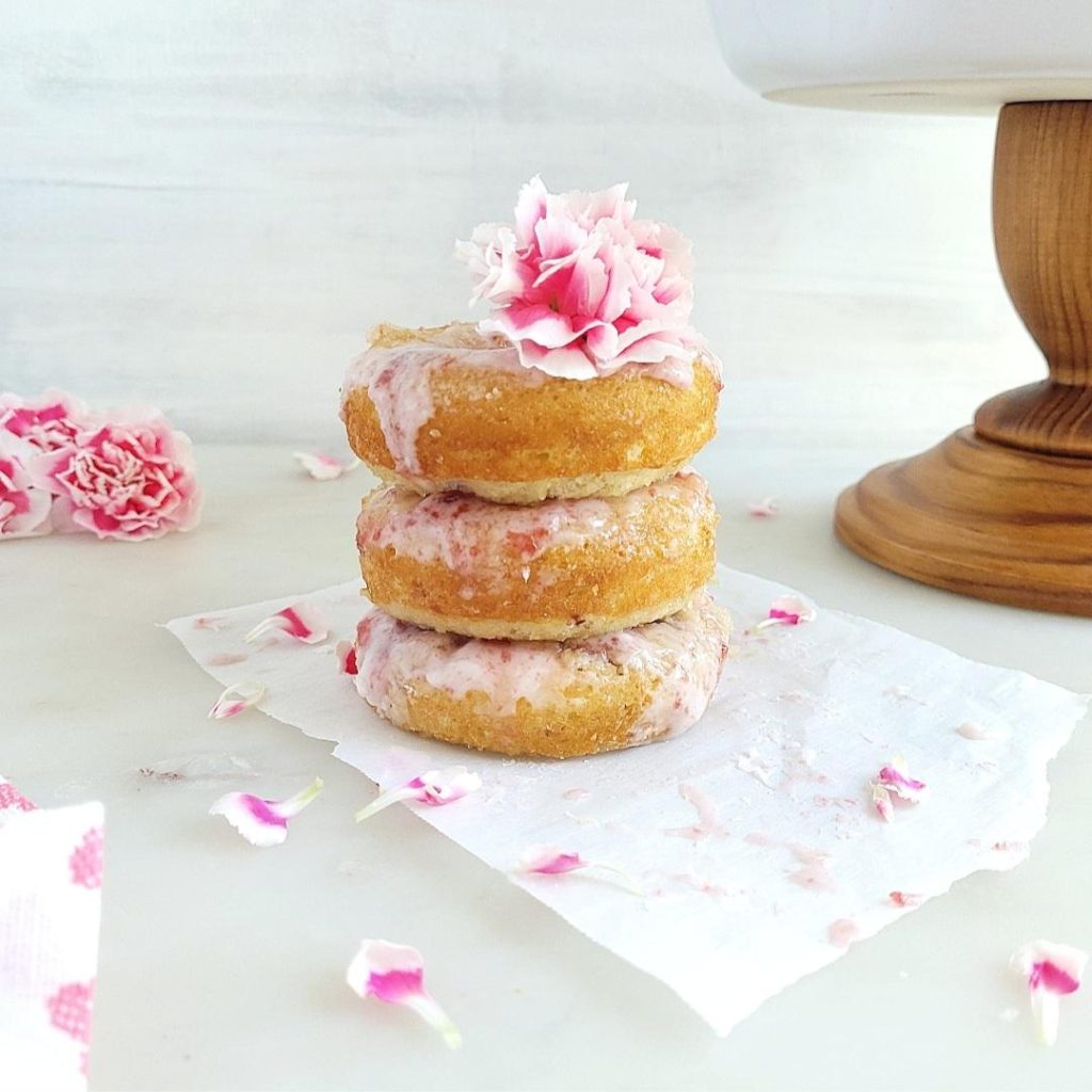 functional image cherry donuts stacked three high donuts have cherry glaze and are garnished with pink carnations