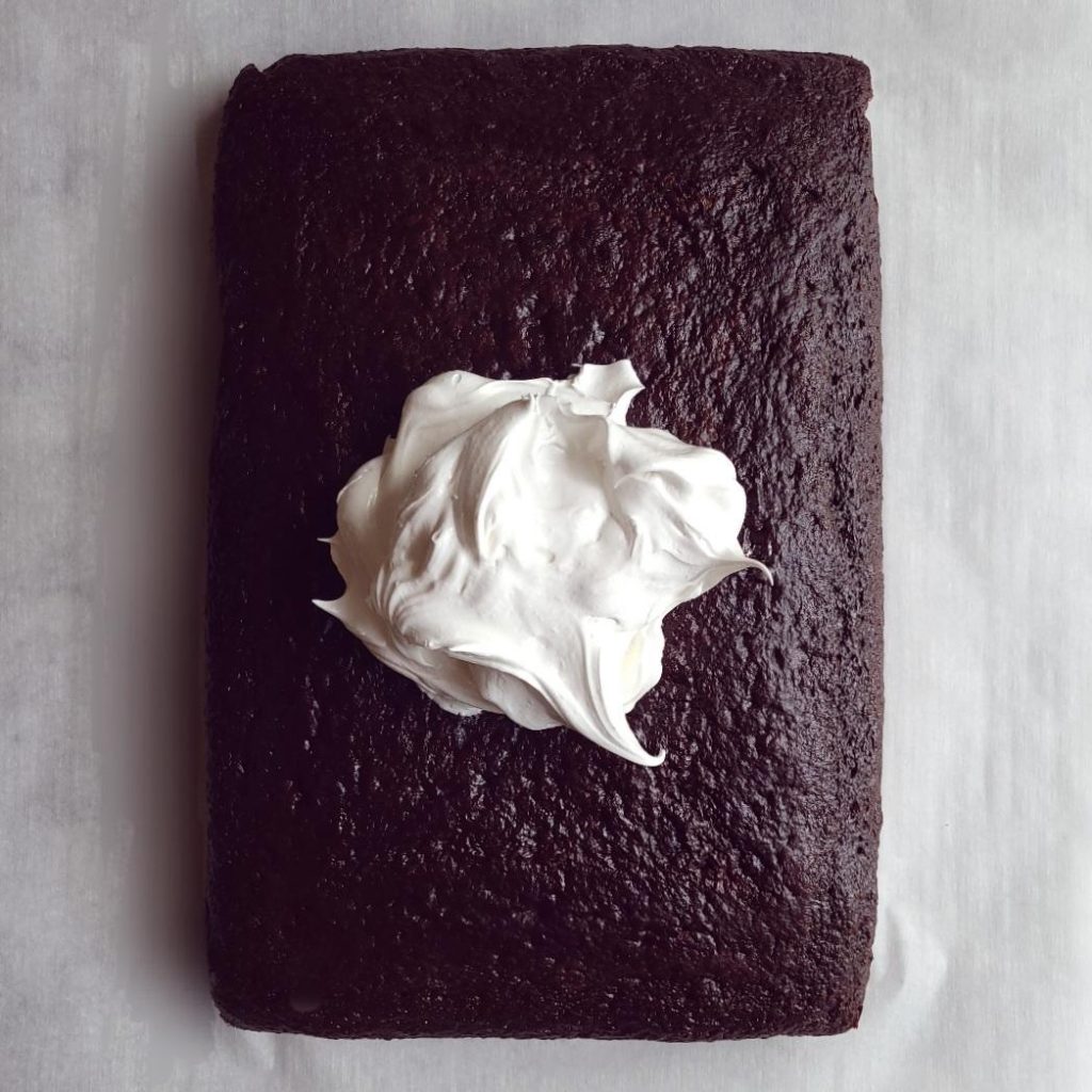 functional image chocolate cake with marshmallow frosting naked cake sheet cake with pile of frosting in the middle unspread top down contrast between dark cake and white frosting