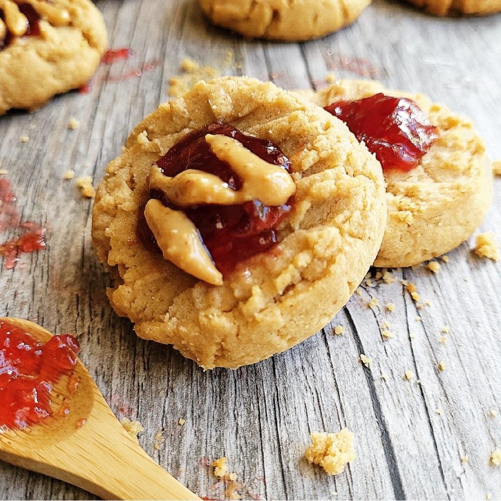 peanut butter and jelly cookies close up of tiled forward cookie with peanut butter drizzle pbj cookies in background