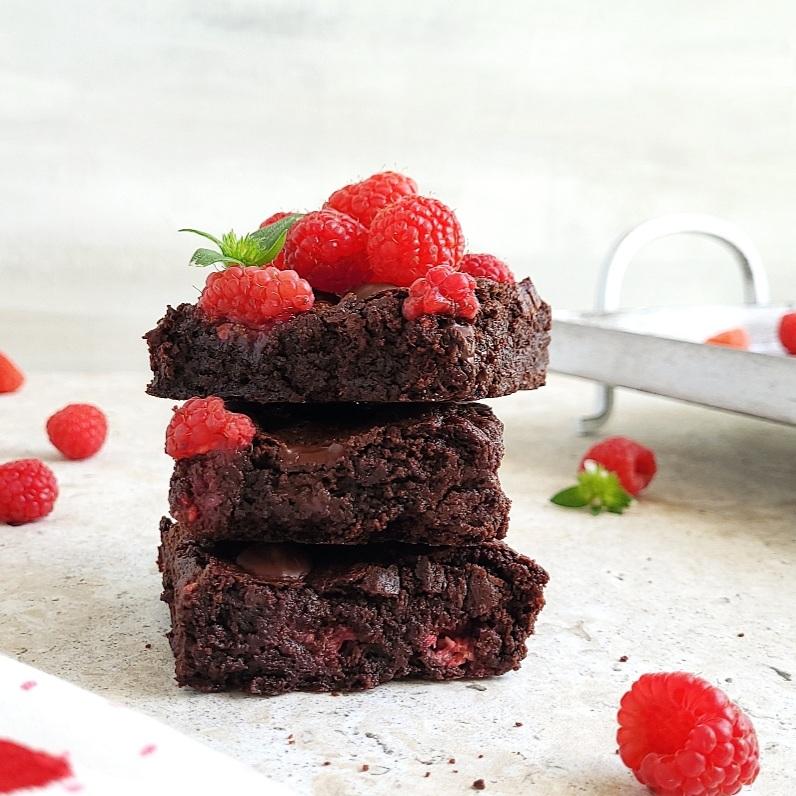 functional image raspberry brownies stacked 3 high with fresh raspberries piled on top side view