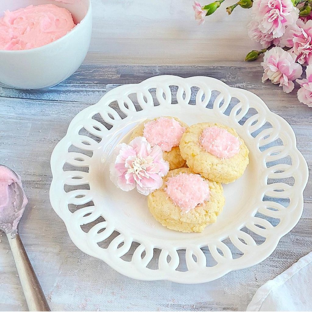 functional image thumbprint cookies with icing pink icing pink sprinkles 3 cookies on a white scalloped plate and a pink carnation top down 