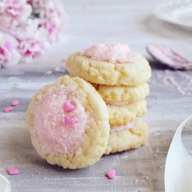 functional image thumbprint cookies with icing stacked 4 high pink icing and pink sprinkles with pink carnations in the background