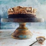 functional image brownie cake with chocolate meringue on a cake stand uncut with blue background