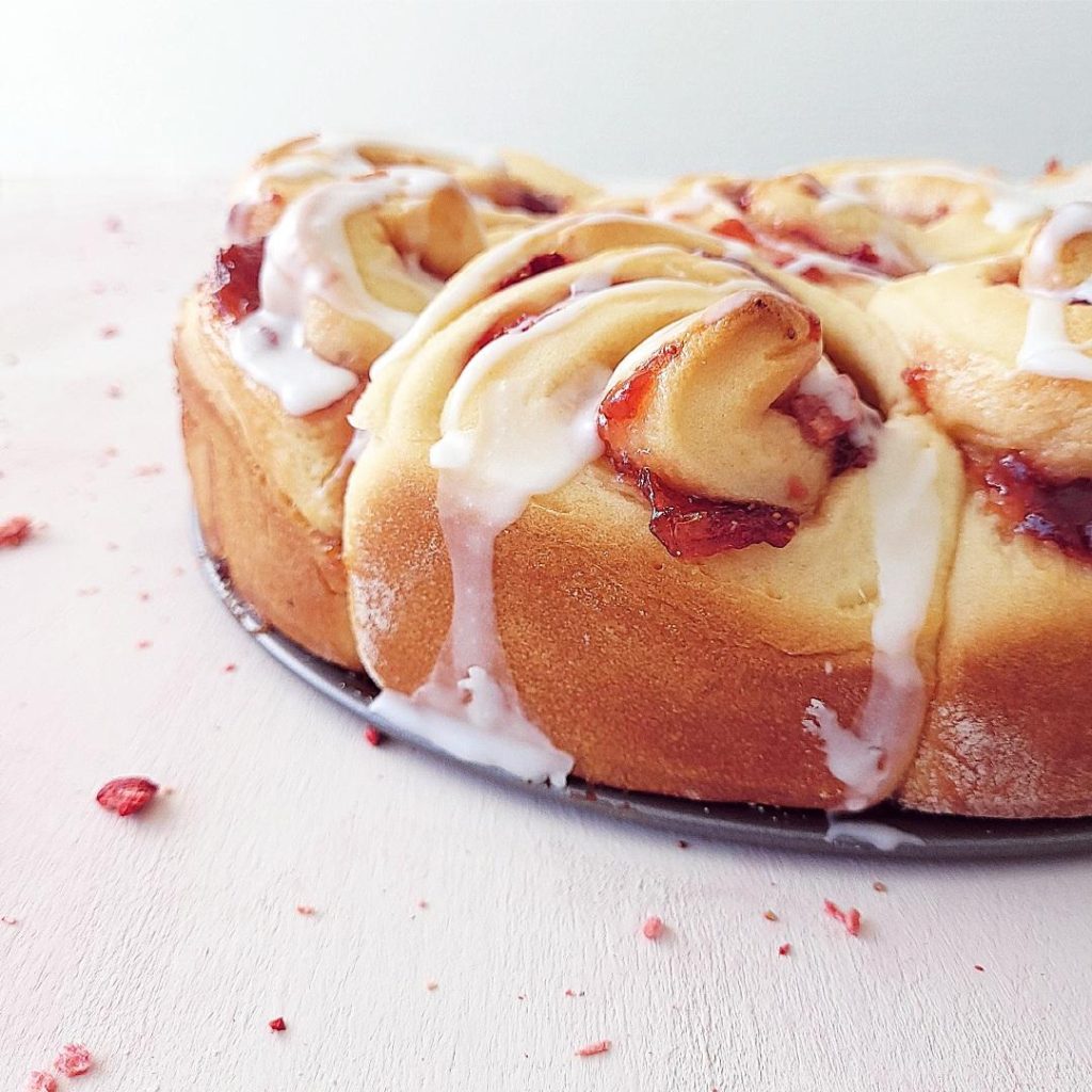 functional image strawberry cinnamon rolls side view with strawberry jam and icing dripping down the sides close up