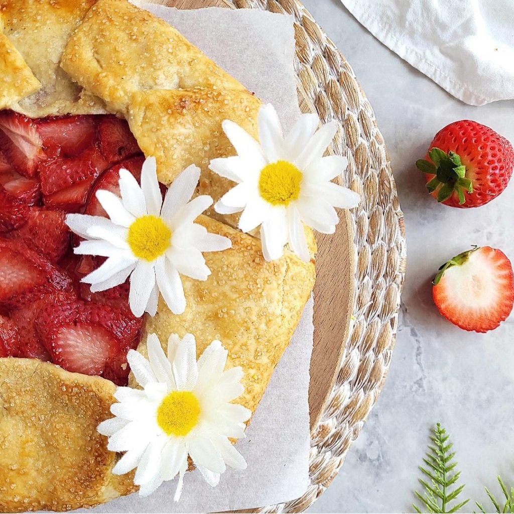 functional image strawberry galette top down close up of half pie with white daisies and fresh strawberries off to the side