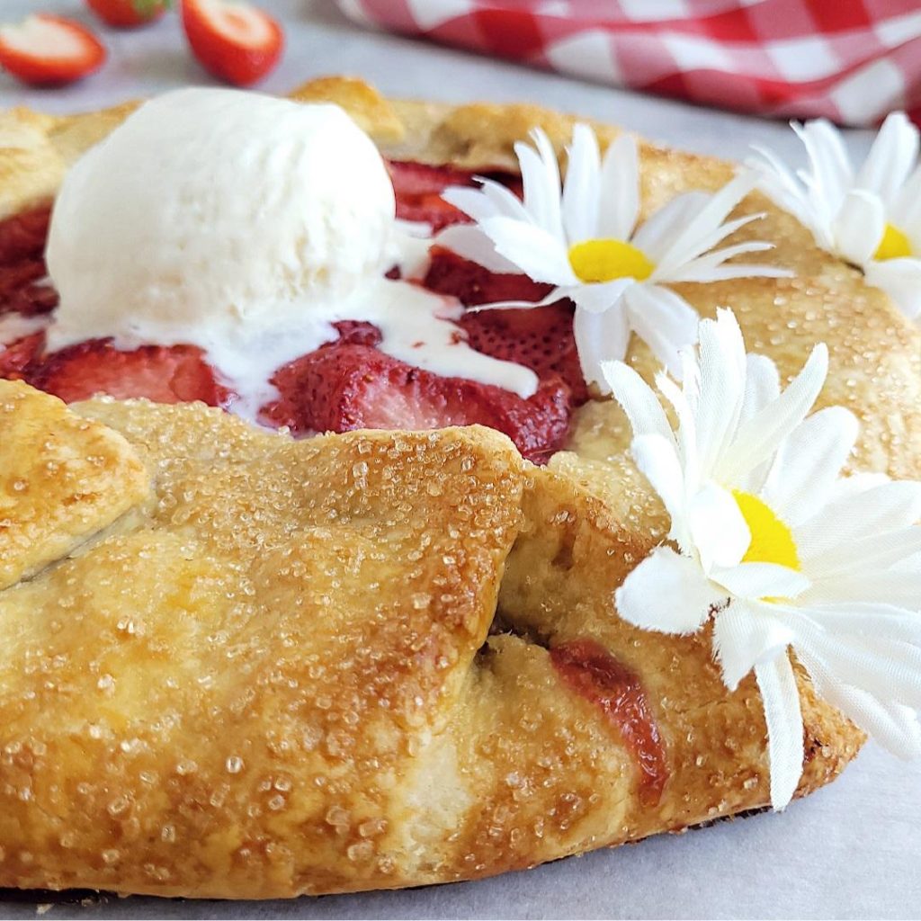 functional image strawberry galette side view close up with a scoop of vanilla ice cream daisies and fresh strawberries in the background