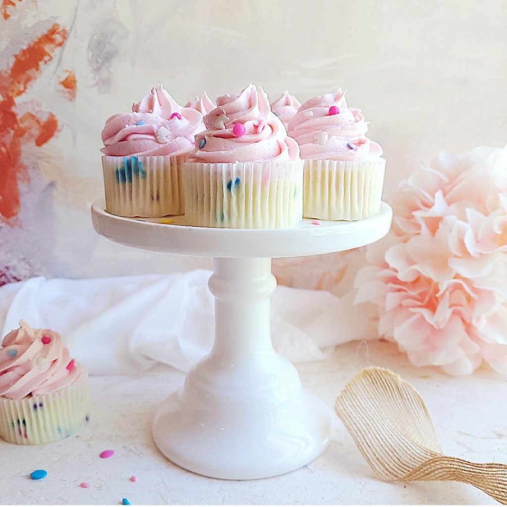 functional image confetti sprinkle cupcakes with pink frosting on a white cake stand