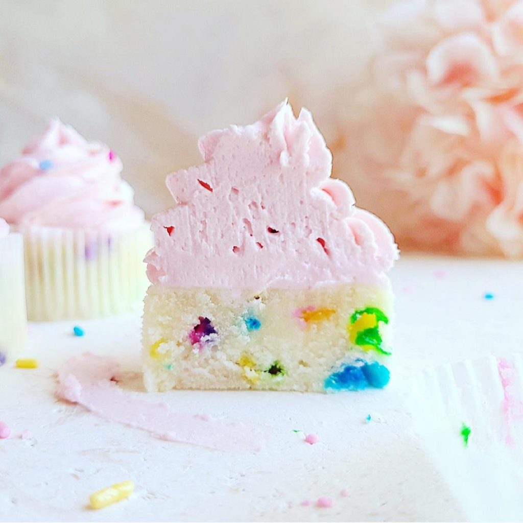 functional image sprinkle cupcakes with pink frosting sliced in half side view to see white cake crumb, colorful sprinkles baked into cupcake