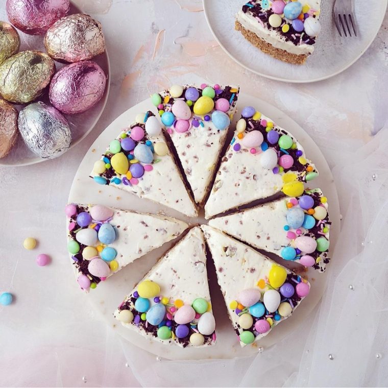 easter cheesecake main image top down view of 8 slices decorated with cadbury mini eggs, easter m&m's, easter sprinkles and chopped chocoalte