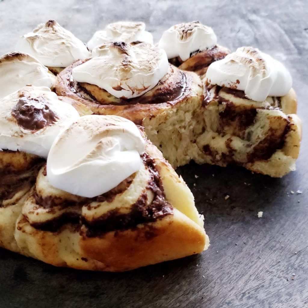functional image smores rolls smores chocolate rolls smores cinnamon buns side view with one bun missing so you can see the swirled layers and homemade marshmallow topping