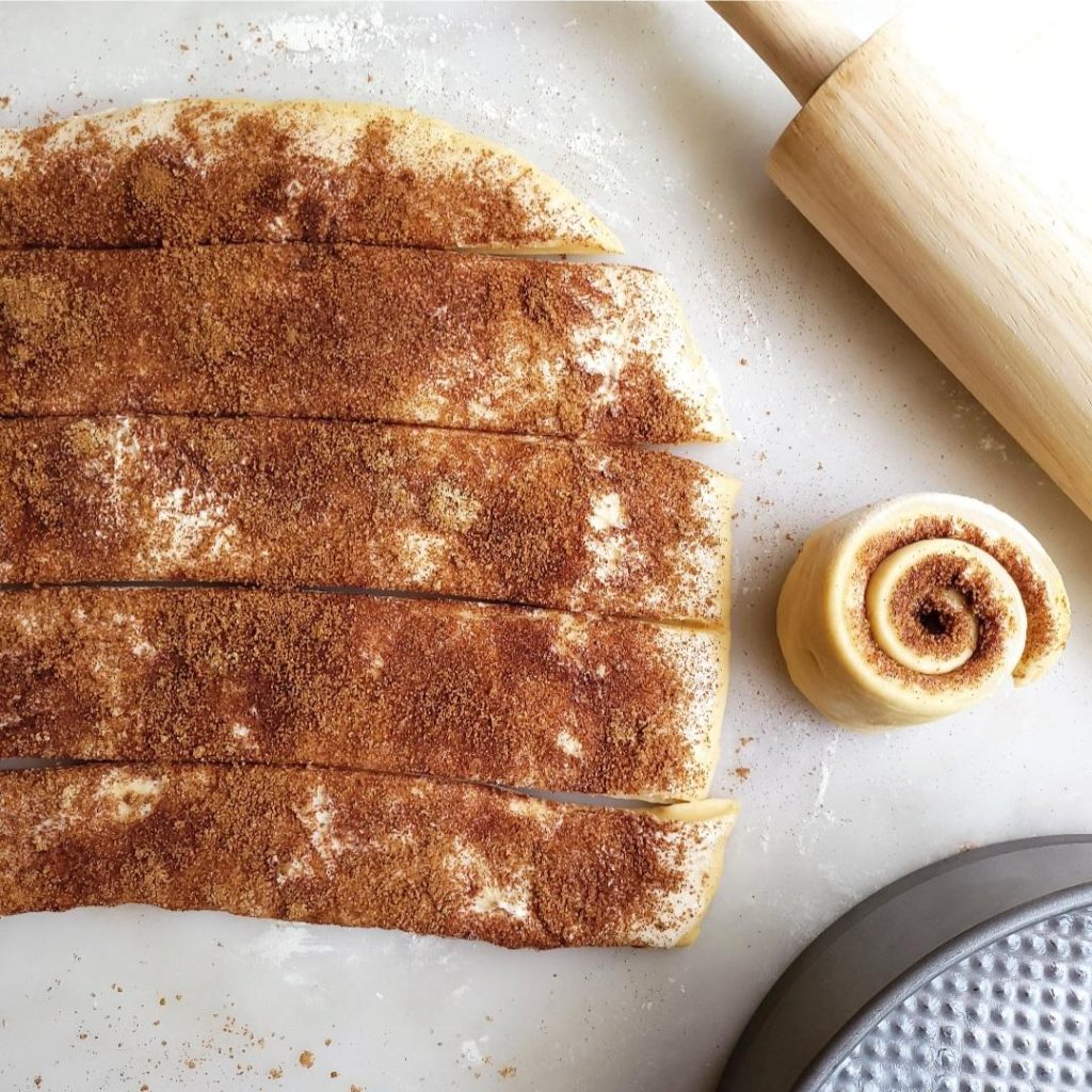 functional image giant cinnamon roll dough with cinnamon sugar cut into strips