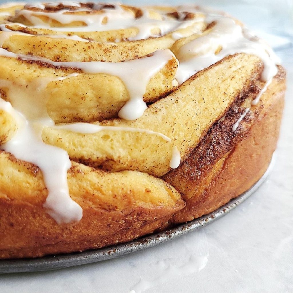 functional image giant cinnamon roll side view with frosting drizzle running down the side