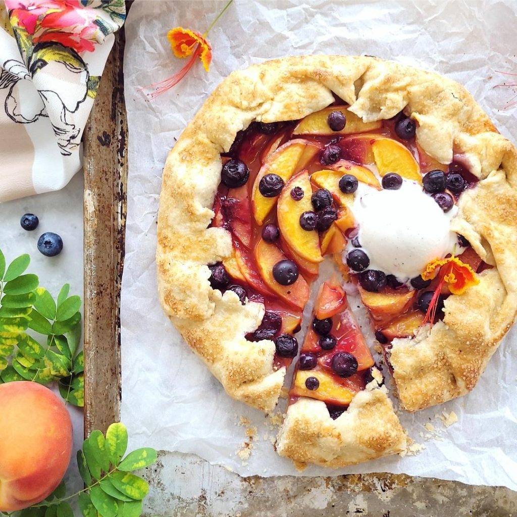 functional image blueberry peach galette top down with a scoop of vanilla ice cream and once slice cut